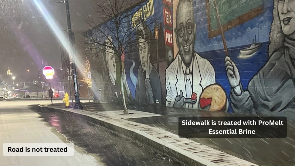 Nighttime snow storm in city setting with a wet sidewalk with no snow accumulation and a road surface heavy with accumulated snow  and the text of “sidewalk is treated with ProMelt Essential Brine” and Road is not treated.